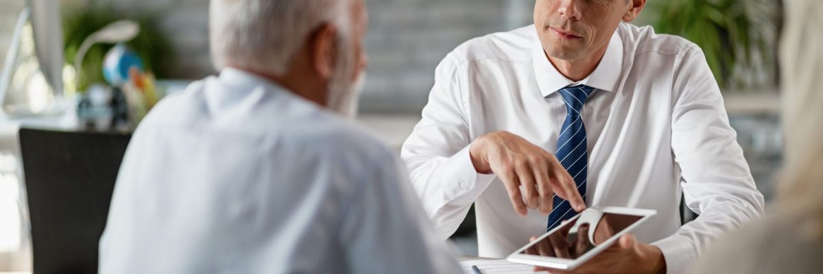 Insurance agents using digital tablet while having a meeting with senior clients in the office.