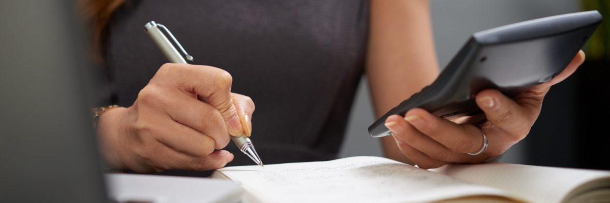 Close-up image of business lady making calculations and taking notes